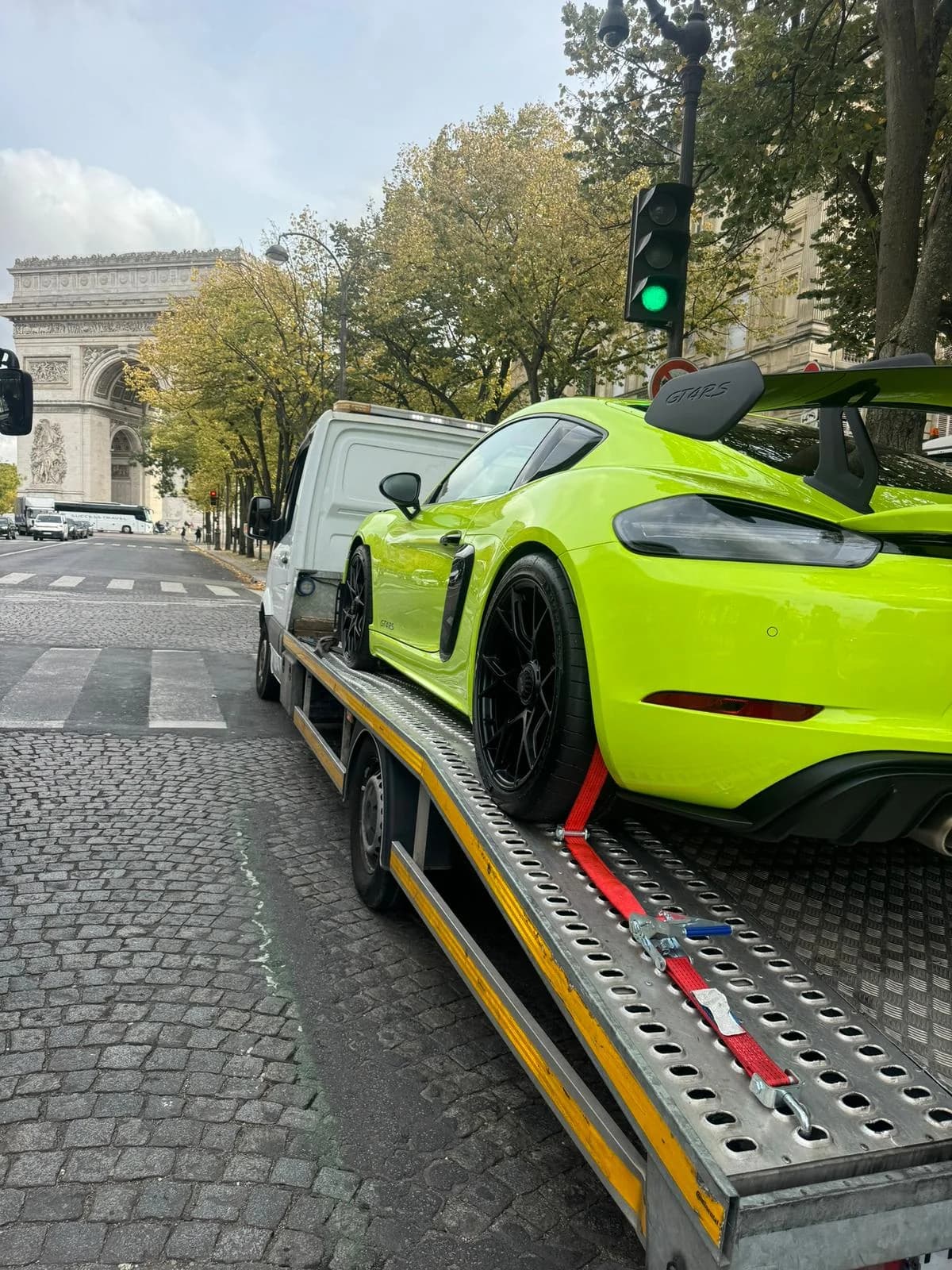 Voiture de sport arrimée sur un plateau, Arc de Triomphe en arrière-plan